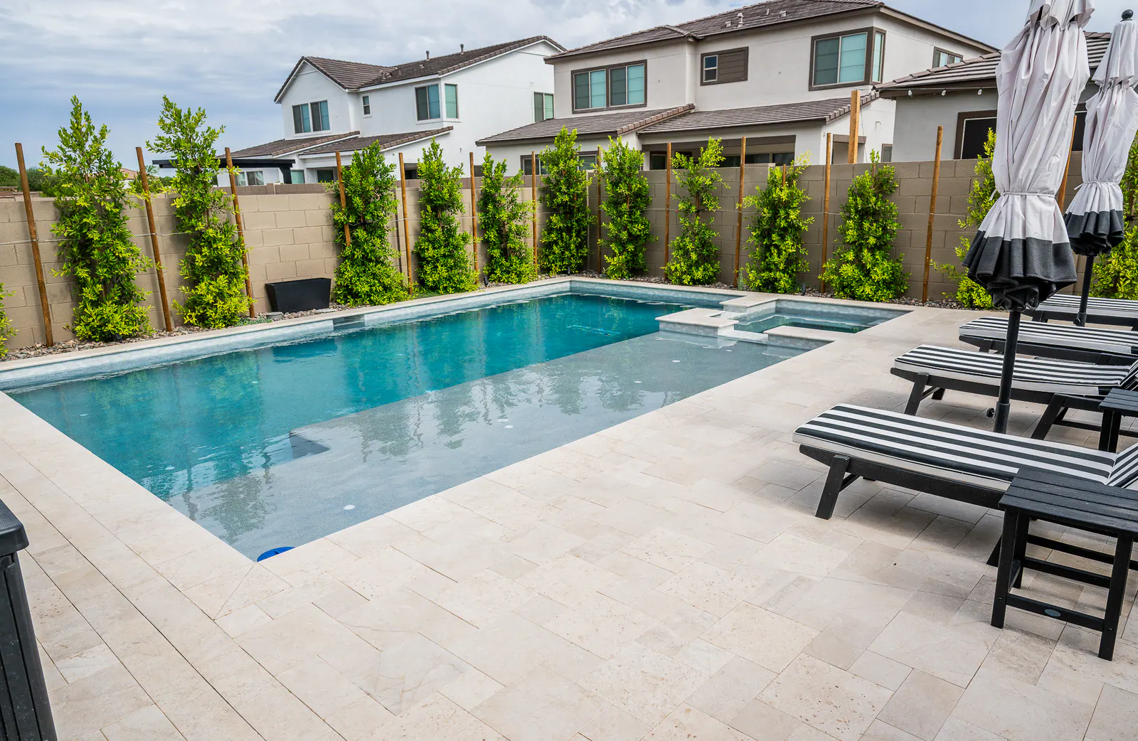 Light-colored paver patio surrounding a modern backyard pool in Arizona